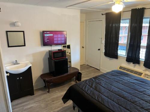 ein Schlafzimmer mit einem Bett und einem Waschbecken sowie einem TV in der Unterkunft Spruce Pine Inn in Spruce Pine
