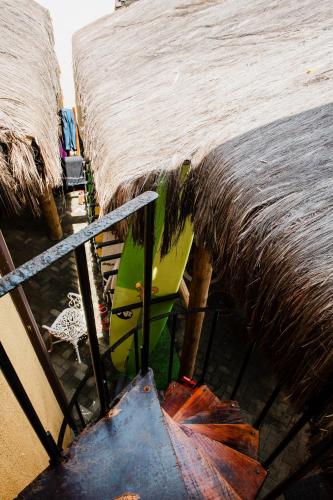 a surfboard sitting next to a thatched roof at Longboard Paradise Surf Club in Rio de Janeiro