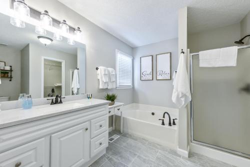 a white bathroom with a tub and a sink at Fully Fenced & Stylish 3BR Near LakePoint Sports in Cartersville