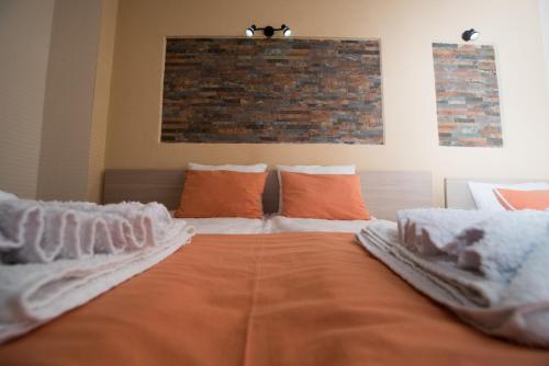 a large bed with white sheets and orange pillows at Villa La Munte in Kruševo