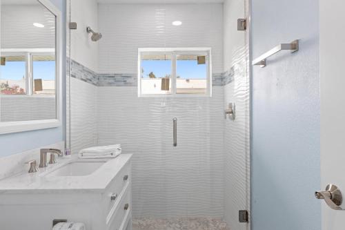 a white bathroom with a shower and a sink at Palm Retreat - Large Cottage on Sanibel Island with Bikes in Sanibel