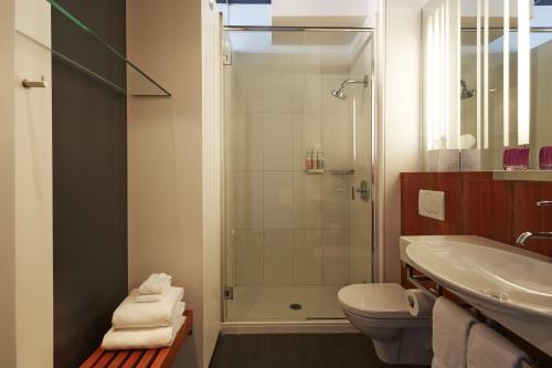 a bathroom with a shower and a toilet and a sink at Hôtel Alt Quartier DIX30 in Brossard