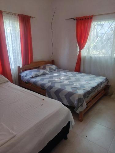 a bedroom with two beds and a window with red curtains at Mí tesorito in Melgar