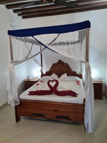 Un dormitorio con una cama con dosel con dos cisnes. en Blue Moon Villa en Pwani Mchangani Mdogo