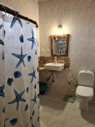a bathroom with a shower curtain with a toilet and a sink at Blue Moon Villa in Pwani Mchangani Mdogo