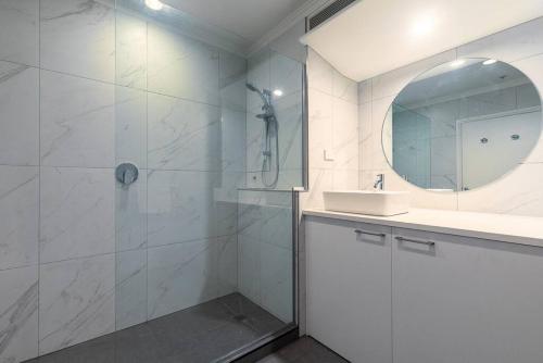 een badkamer met een douche, een wastafel en een spiegel bij Happy Days in Auckland