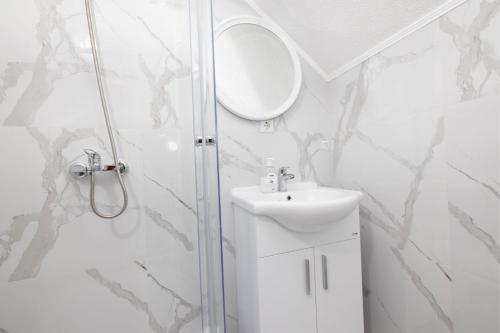 a bathroom with a shower and a sink and a mirror at Apartman BARIŠIĆ 2 in Kupres