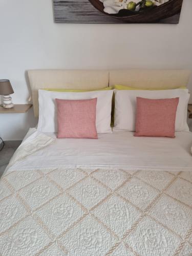 een wit bed met twee roze kussens erop bij B&B Casa Roel in Sant'Agnello