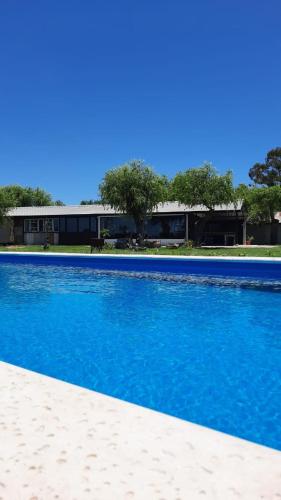 a swimming pool with blue water in front of a building at La Quinta de LOS ABU in Ramallo