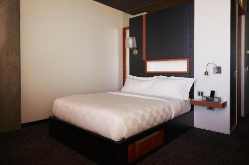 a hotel room with a bed with white sheets at Hôtel Alt Quartier DIX30 in Brossard