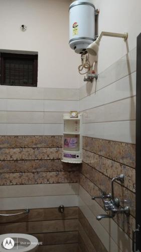 a bathroom with a toilet and a light on the wall at Guru Kripa Guest House ( Home Stay ) in Ayodhya