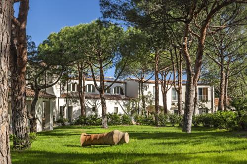 una grande casa bianca con alberi nel cortile di Is Arenas Resort a Narbolia