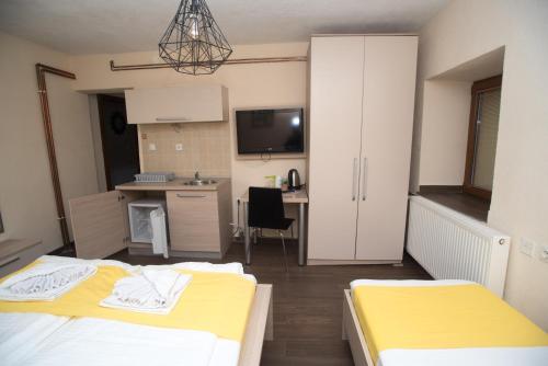 a bedroom with two beds and a kitchen with a desk at Villa La Munte in Kruševo