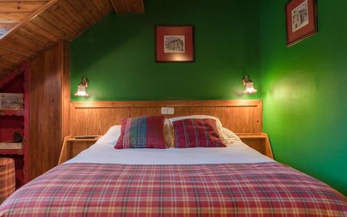 a green bedroom with a bed with two pillows at Hotel Aran La Abuela in Vielha