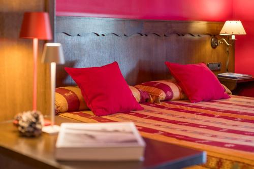 a bedroom with a bed with red pillows on it at Hotel Aran La Abuela in Vielha