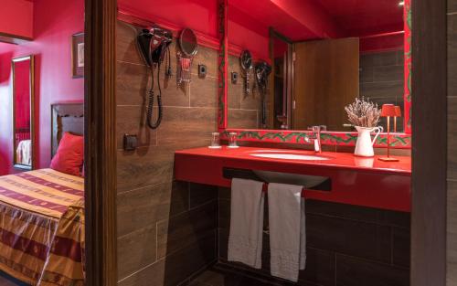 a red bathroom with a sink and a mirror at Hotel Aran La Abuela in Vielha