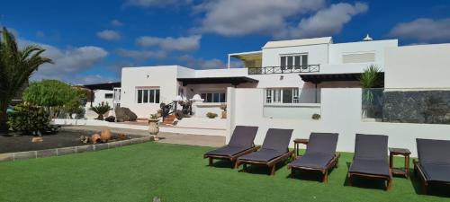 un patio con sillas y una casa en Renovated Villa Mahalo with swimming pool & tennis court en Tías