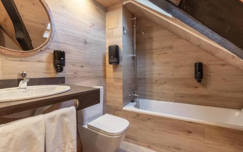 a bathroom with a toilet and a sink and a tub at Hotel Aran La Abuela in Vielha