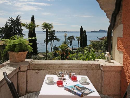 a table and chairs with a view of the water at Hotel Bellevue in Gardone Riviera