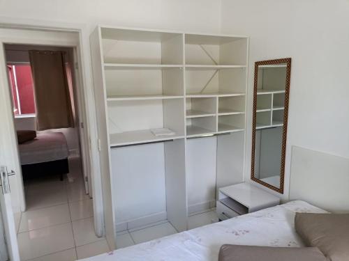 a bedroom with white shelves and a mirror and a bed at Apartamento em Caiobá Matinhos próximo à Praia Brava! in Matinhos