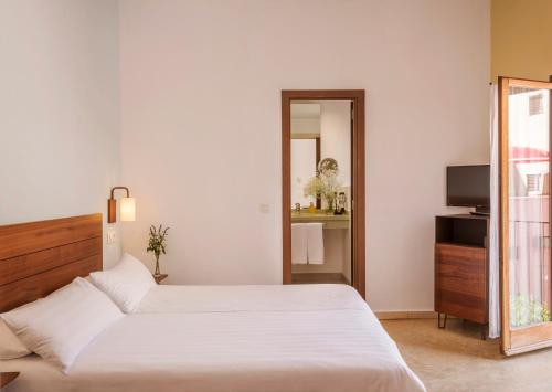 a bedroom with a large white bed and a mirror at Palau Sa Font in Palma de Mallorca