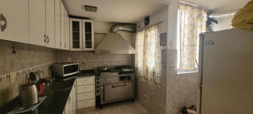 a small kitchen with white cabinets and a refrigerator at Dpto centrico con parrilla integrada in Mar del Plata