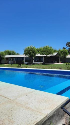 a large blue swimming pool in front of a house at La Quinta de LOS ABU in Ramallo