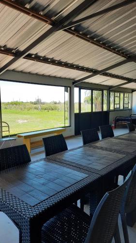 a table and chairs in a room with a view of a field at La Quinta de LOS ABU in Ramallo