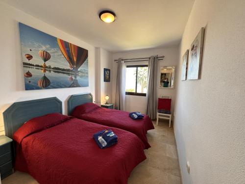 a bedroom with two beds with red sheets and a window at 111 marina duquesa in Manilva