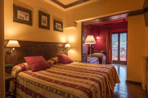 a hotel room with a large bed with red pillows at Hotel Aran La Abuela in Vielha