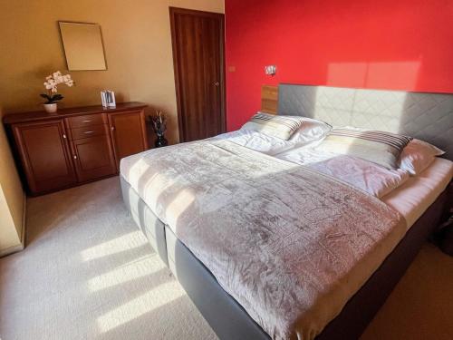 1 cama grande en un dormitorio con una pared roja en Tri Štíty Apartment with Tatra View Terrace en Veľká Lomnica
