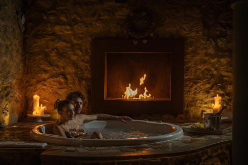 a woman sitting in a bath tub in front of a fireplace at TORRE GIARDINO SEGRETO B&B- Borgo Capitano Collection - Albergo diffuso in San Quirico dʼOrcia