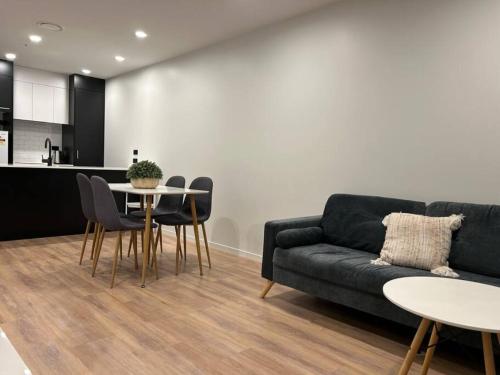 een woonkamer met een bank en een tafel en stoelen bij Top Floor Vincent in Auckland
