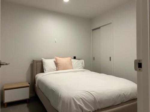 een slaapkamer met een groot wit bed en een roze kussen bij Top Floor Vincent in Auckland