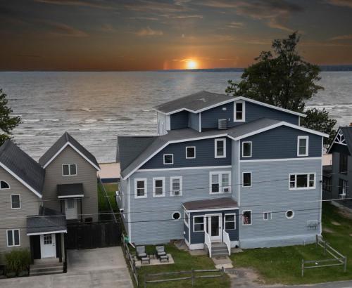 a large house with the sun setting over the water at " The Penthouse" Historic Oneida Lakefront Condo 5 in Blossvale