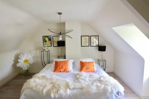 1 dormitorio con 1 cama blanca y 2 almohadas de color naranja en Jolie Chaumière avec jardin privé à 400m des sentiers côtiers - animaux acceptés, en Arradon