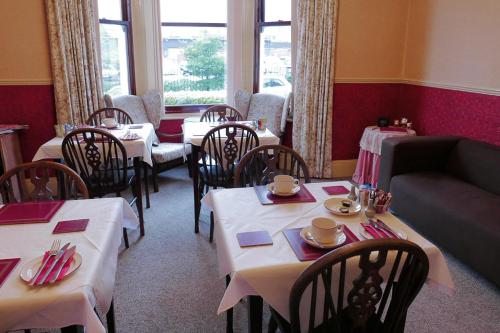 a restaurant with tables and chairs and a couch at Abbey Guest House in Norwich