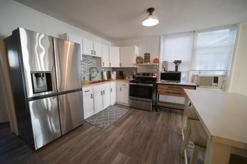 uma cozinha com um frigorífico de aço inoxidável e armários brancos em The Historic Oneida Lake House - Condo 1 em Blossvale