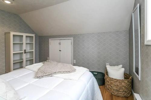a bedroom with a white bed and a gray wall at Luxurious 5 BR Home in the Heart of Sylvan Beach in Blossvale
