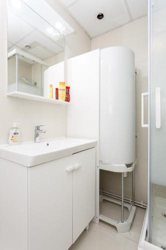 une salle de bain blanche avec un lavabo et un miroir dans l'établissement Le blanc mesnil 23 Abbé niort A 1er ETG gauche, au Blanc-Mesnil