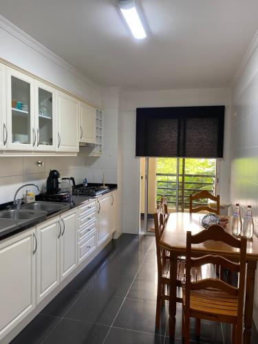 uma cozinha com armários brancos, uma mesa e uma sala de jantar em Apartamento Costa Do Sol V no Funchal