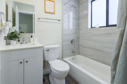 a white bathroom with a toilet and a tub and a sink at Apartment in the Famous Calle Ocho in Miami in Miami