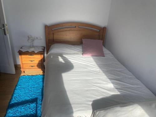 a bed with a wooden headboard and a pink pillow at BAHIÑA MAR in Baiona