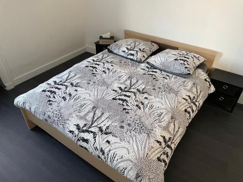 1 cama con edredón blanco y negro y 2 almohadas en Appartement proche de la gare de Roanne, en Roanne
