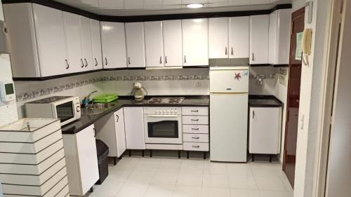 eine Küche mit weißen Geräten und weißen Schränken in der Unterkunft Acogedor Apartamento in Hospitalet de Llobregat