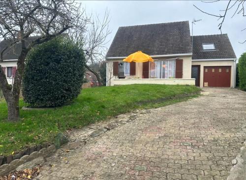 uma casa com um guarda-chuva amarelo em frente em Charmante maison 10 mn Center Parcs Ailette em Laon