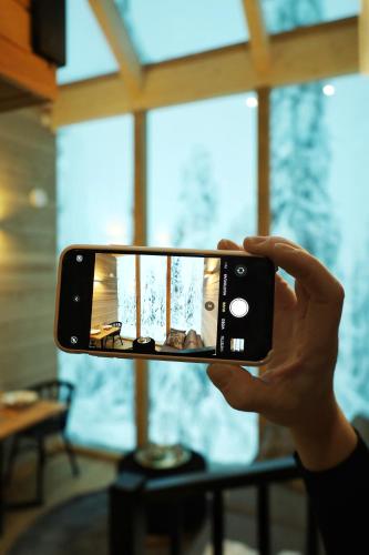 a person taking a picture with their cell phone at Villa Auroras Pöllö in Syöte
