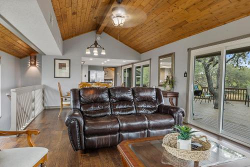 a living room with a leather couch and a table at Wine Country Retreat – with a lake view! in Spicewood