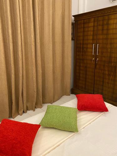 two red and green pillows sitting on top of a bed at Sunshine Holiday Home at Wattala in Wattala