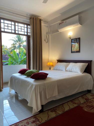 a bedroom with a large white bed with a window at Sunshine Holiday Home at Wattala in Wattala